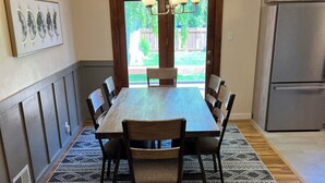 A dining area with a wooden table and chairs, a patterned rug, and a view through a door to a backyard. - Centrally located home in the heart of Twin Falls.  (Twin Falls)