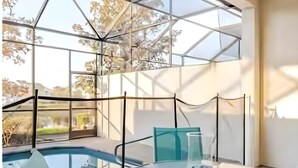 A modern indoor pool area with glass walls, a round table, and chairs. - Universal Studios.Townhome.3BR.Private Pool! (Davenport)