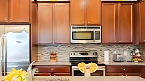 A kitchen with wooden cabinets, a stainless steel refrigerator, a microwave, an oven, and a marble countertop. - Universal Studios.Townhome.3BR.Private Pool! (Davenport)