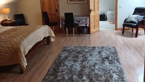Ein Schlafzimmer mit Bett, Schreibtisch, Stuhl, Teppich und einem Bild an der Wand.
