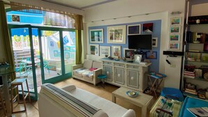 A living room with a sofa, a coffee table, a TV, and a bookshelf. - Luxury sweet in the center of Capri (Capri)