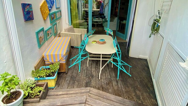 A cozy outdoor patio with a round table and turquoise chairs, surrounded by potted plants and framed artwork. - Luxury sweet in the center of Capri (Capri)