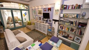 A cozy living room with a sofa, a coffee table, a bookshelf, and a TV. - Luxury sweet in the center of Capri (Capri)