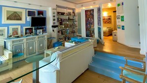 A modern living room with a glass dining table, a white sofa, and a wooden floor. - Luxury sweet in the center of Capri (Capri)
