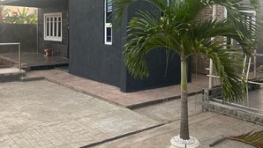 Un edificio moderno con una antena parabólica, ventanas amplias y una palmera en primer plano.