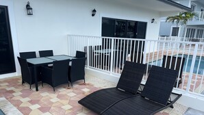 Eine Terrasse im Freien mit Pool, Tisch mit Stühlen und Liegestühlen.