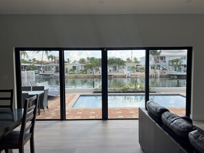 A modern living room with a large sliding glass door leading to a pool area.
