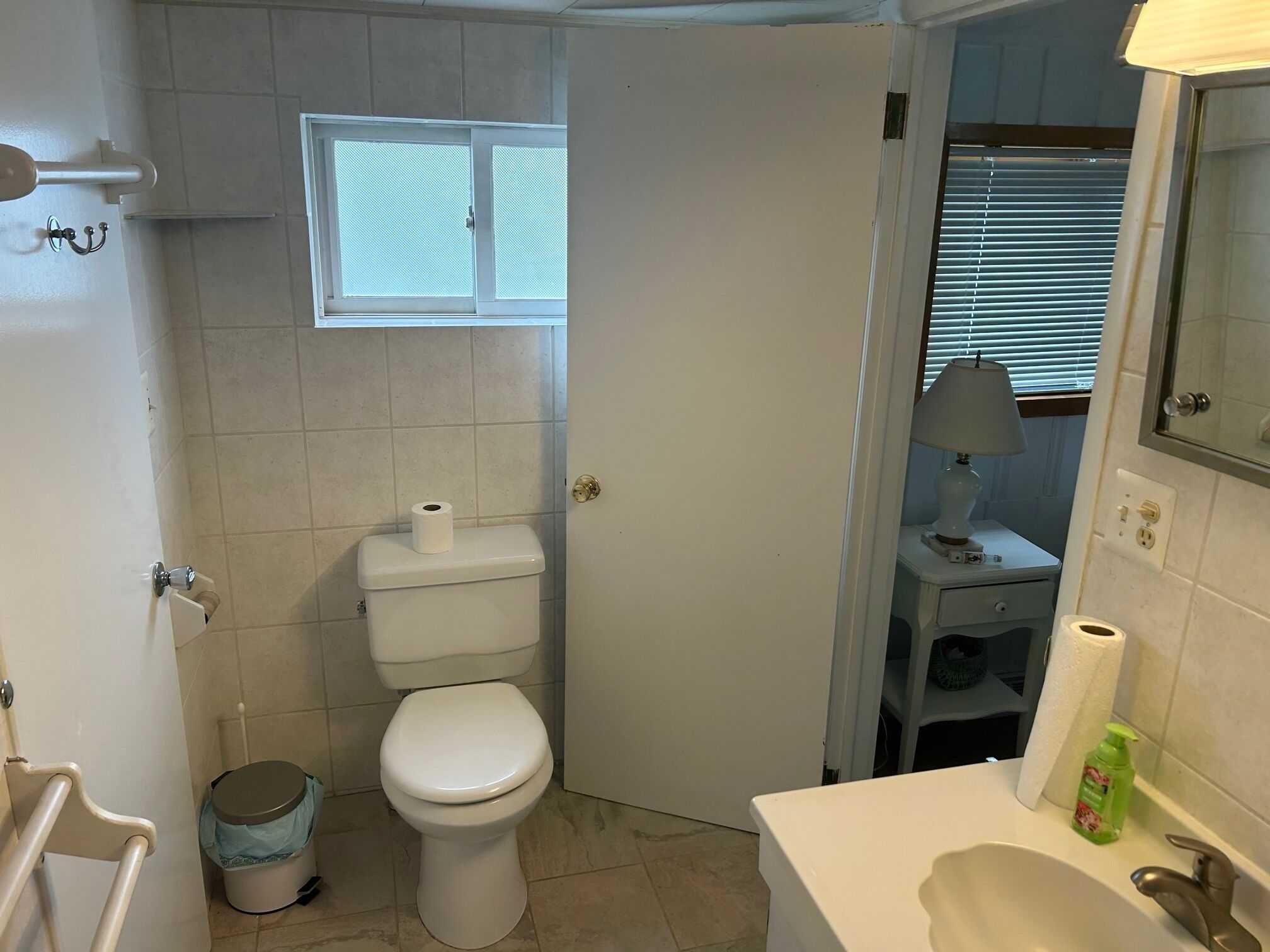 Une salle de bain avec des toilettes, une fenêtre, un lavabo et un miroir.
