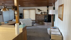 Una sala de estar acogedora con chimenea, un sofá, una mesa de comedor y un televisor.