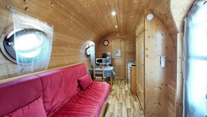 Un espacio interior compacto con un sofá rojo, una kitchenette y una pequeña zona de comedor.