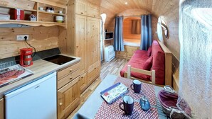 Una cabaña de madera compacta con kitchenette, comedor y zona de descanso.