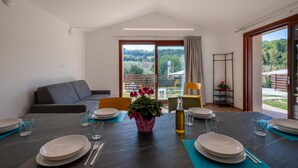 Un comedor moderno con una mesa preparada para cuatro personas, un sofá y vistas al exterior.