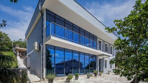 Ein modernes, zweistöckiges Gebäude mit großen Glasfenstern und einem Balkon mit blauen Geländern.