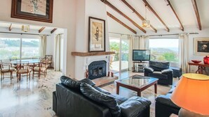 Amplia sala de estar con chimenea, televisor y comedor.
