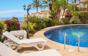 Un espace piscine comprenant des chaises longues, une piscine et une vue sur la mer.
