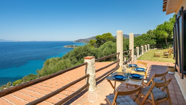 Une terrasse avec une table dressée pour le repas, offrant une vue sur un paysage côtier.