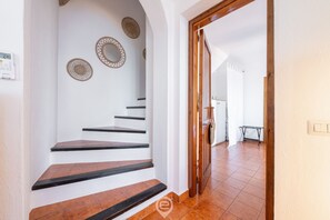 A staircase with white walls and brown steps leading to a room with a wooden door.