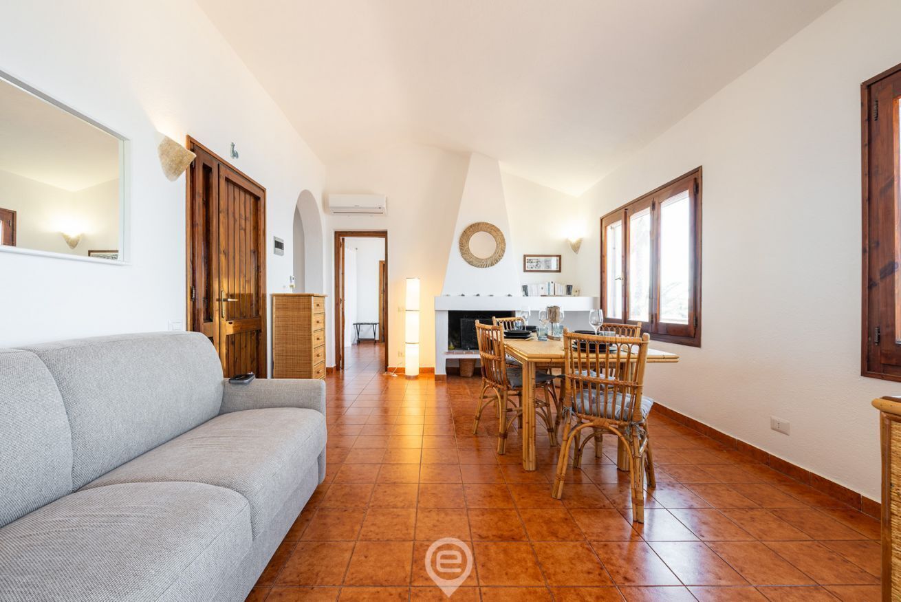Un grand espace de vie comprenant un canapé, une table à manger avec des chaises, et une cuisine à l’arrière-plan.