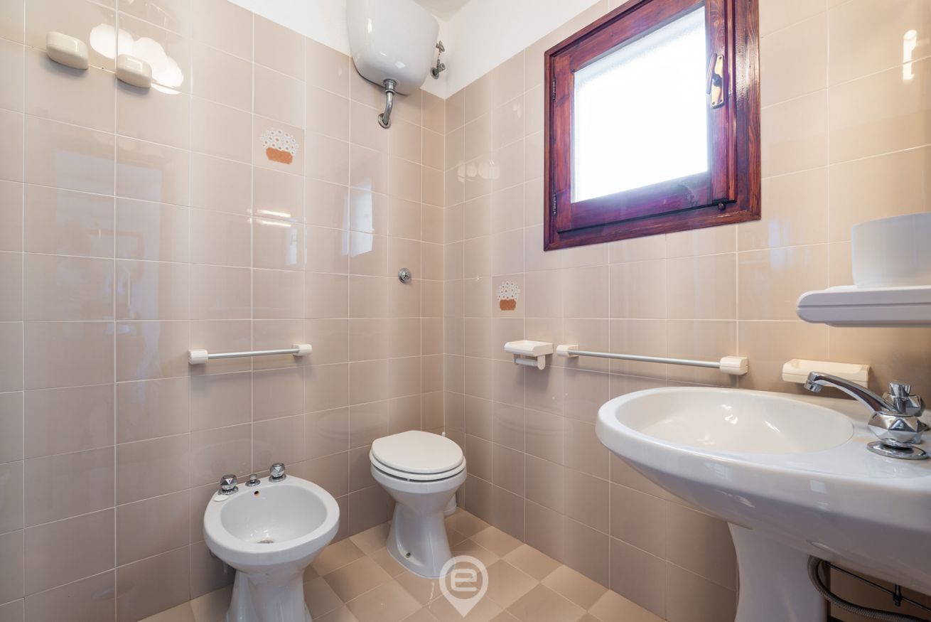 Een witte badkamer met toilet, bidet en wastafel.