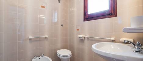 Een witte badkamer met toilet, bidet en wastafel.