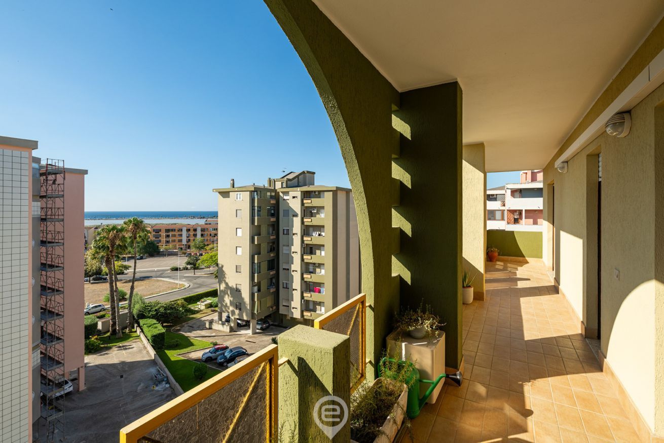 Un balcon donnant sur un quartier résidentiel, avec vue sur un immeuble à plusieurs étages et une plage.