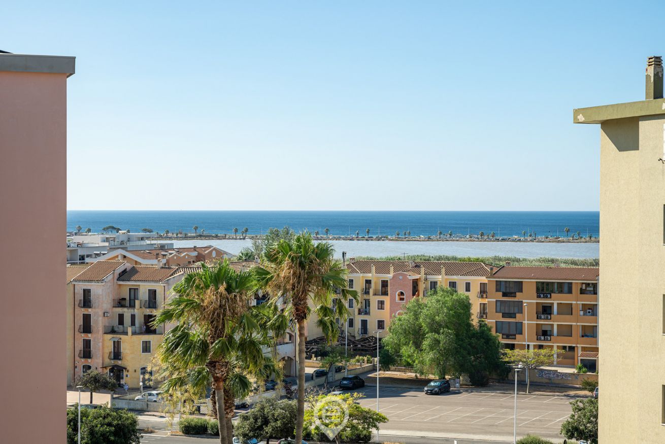 Una zona residencial costera con edificios, un estacionamiento y vistas al mar.
