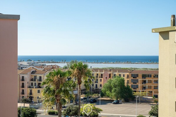A coastal residential area with buildings, a parking lot, and a view of the sea.