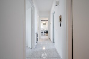 A modern, well-lit hallway leading to a bathroom with a sink and mirror.