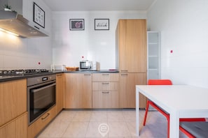 Une cuisine moderne avec des armoires en bois, un four encastré, un four à micro-ondes et un dosseret de carrelage blanc.