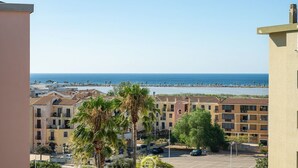 A coastal residential area with buildings, a parking lot, and a view of the sea. - Sunset Oasis Apartment (Quartu Sant'Elena)