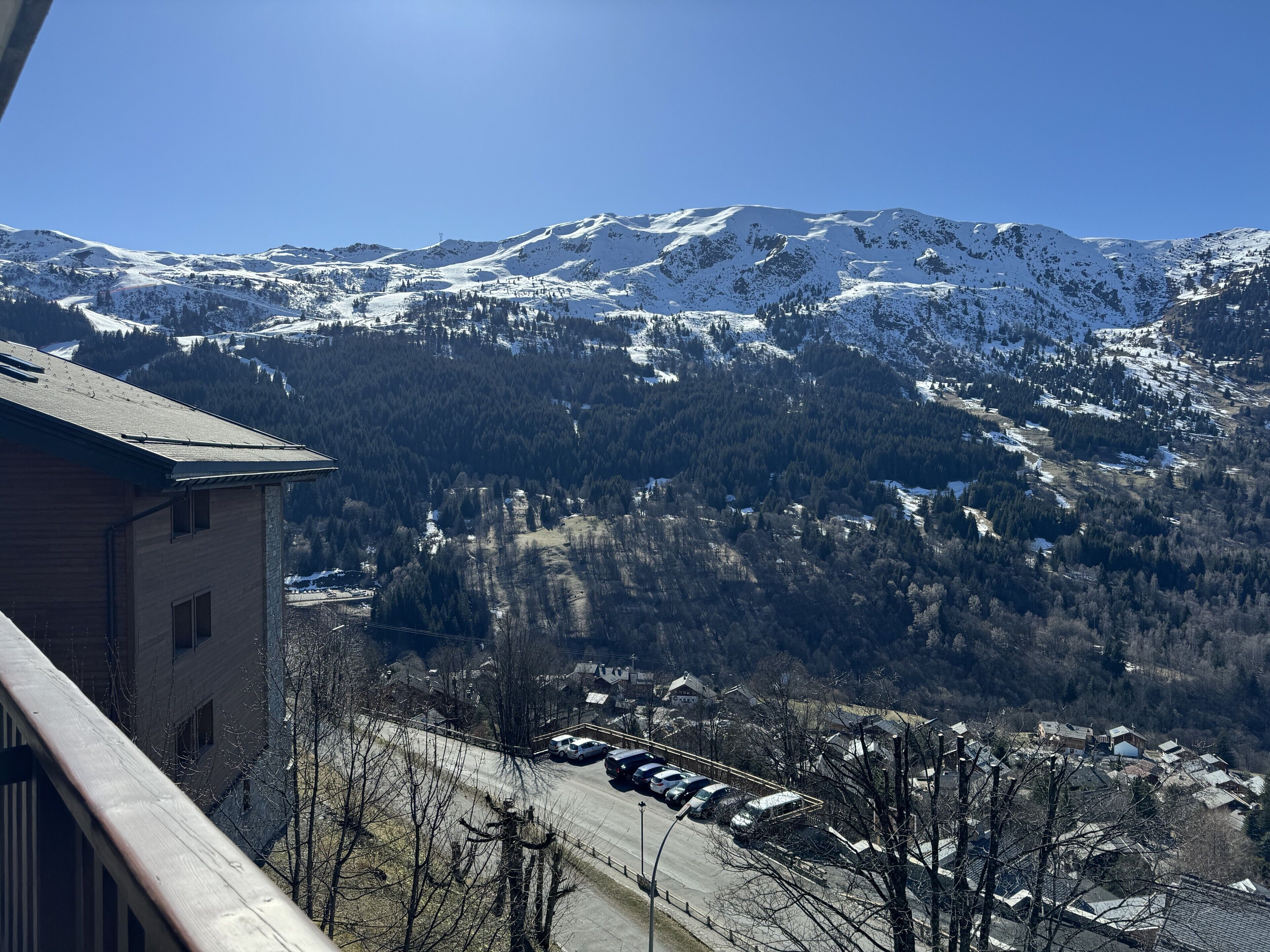 Paisatge de muntanya amb cims nevats i una població a la base.