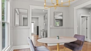 A dining area with a round table, two chairs, and a chandelier. - Airport Cottage  (East Point)