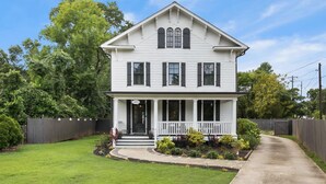 A two-story white house with a front porch, a well-maintained lawn, and a wooden fence. - Airport Cottage  (East Point)
