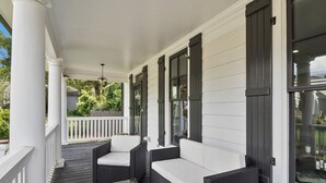 A covered porch with wicker furniture and a glass table. - Airport Cottage  (East Point)