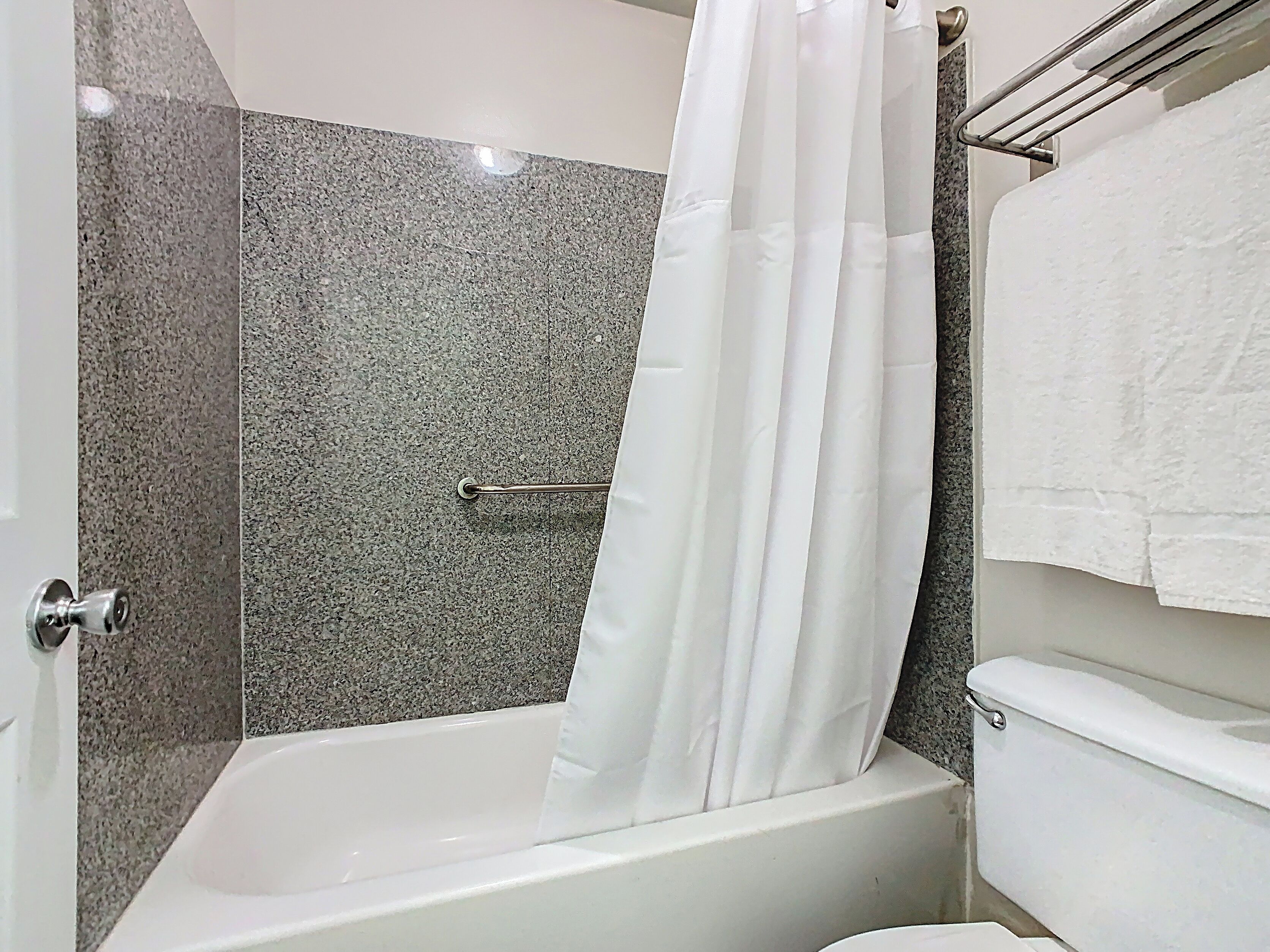 A bathroom with a bathtub, a toilet, and a shower curtain.