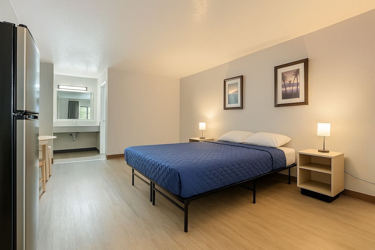 A bedroom with a bed, bedside tables, and a view of the bathroom.