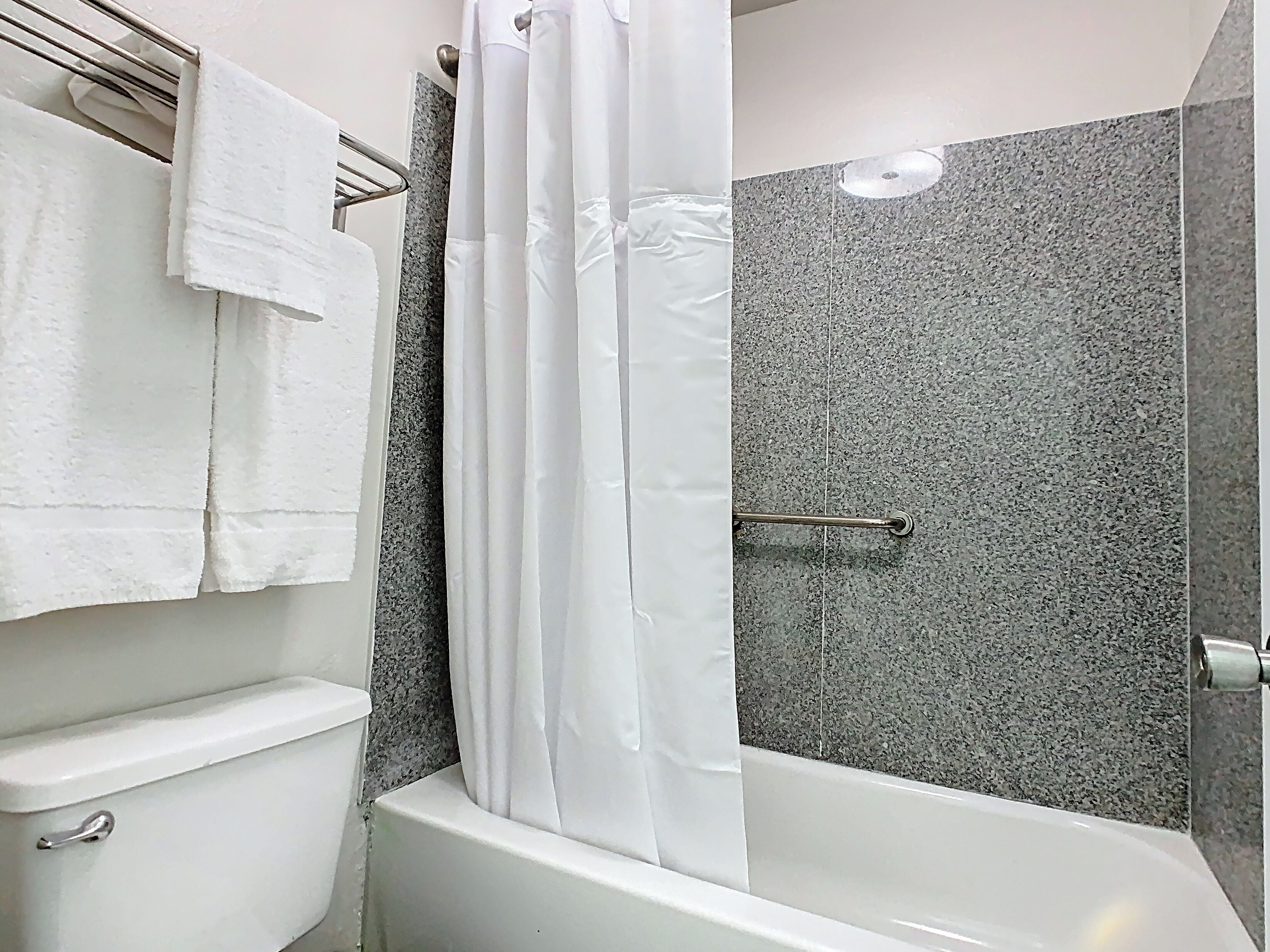 A bathroom with a white bathtub, a shower curtain, and a toilet.