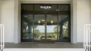 Een hotelingang met een 'Stayable' bord, een glazen deur en uitzicht op de omgeving.