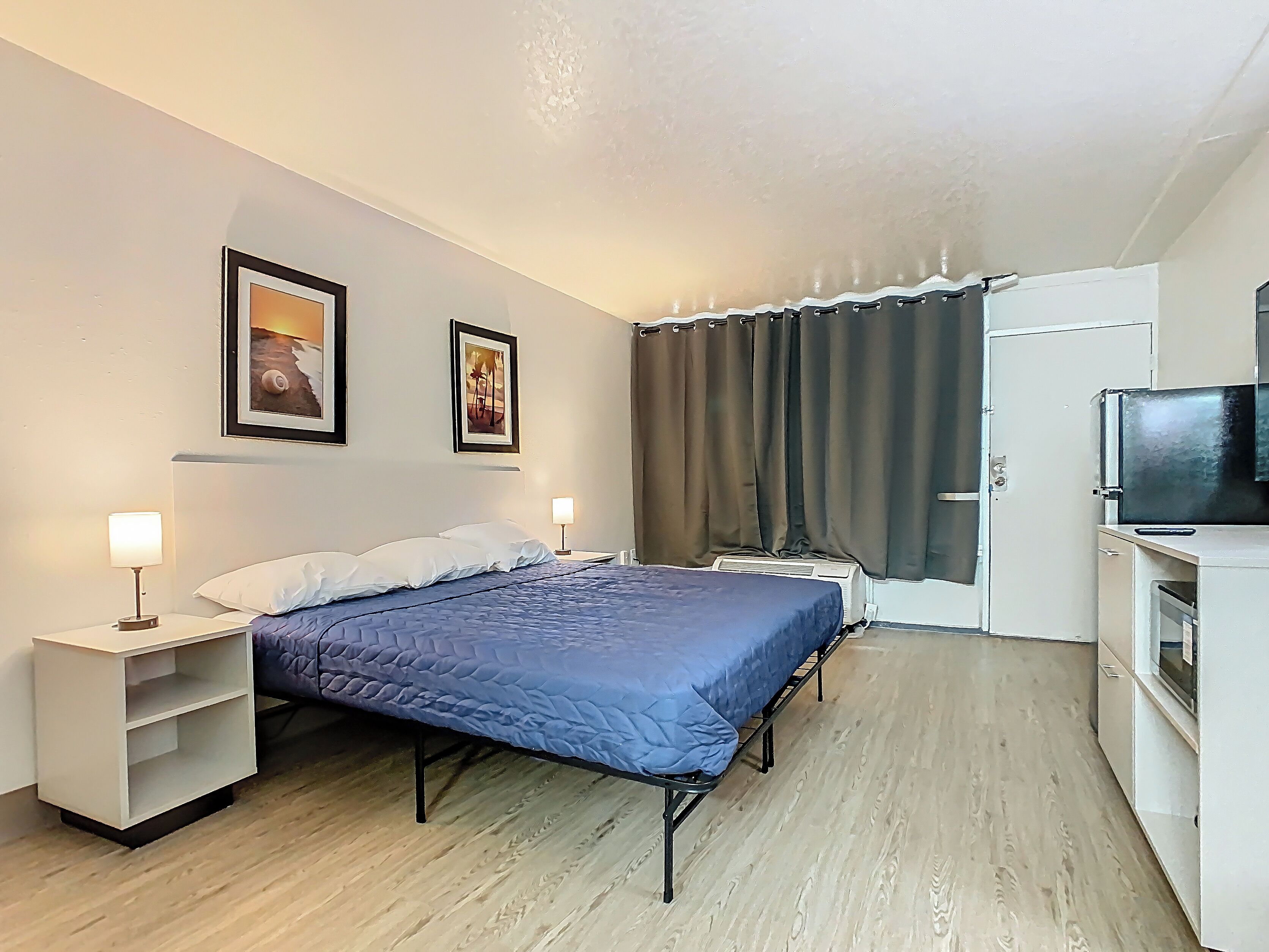 Une chambre à coucher comprenant un lit, deux tables de chevet avec des lampes, une armoire et un téléviseur.