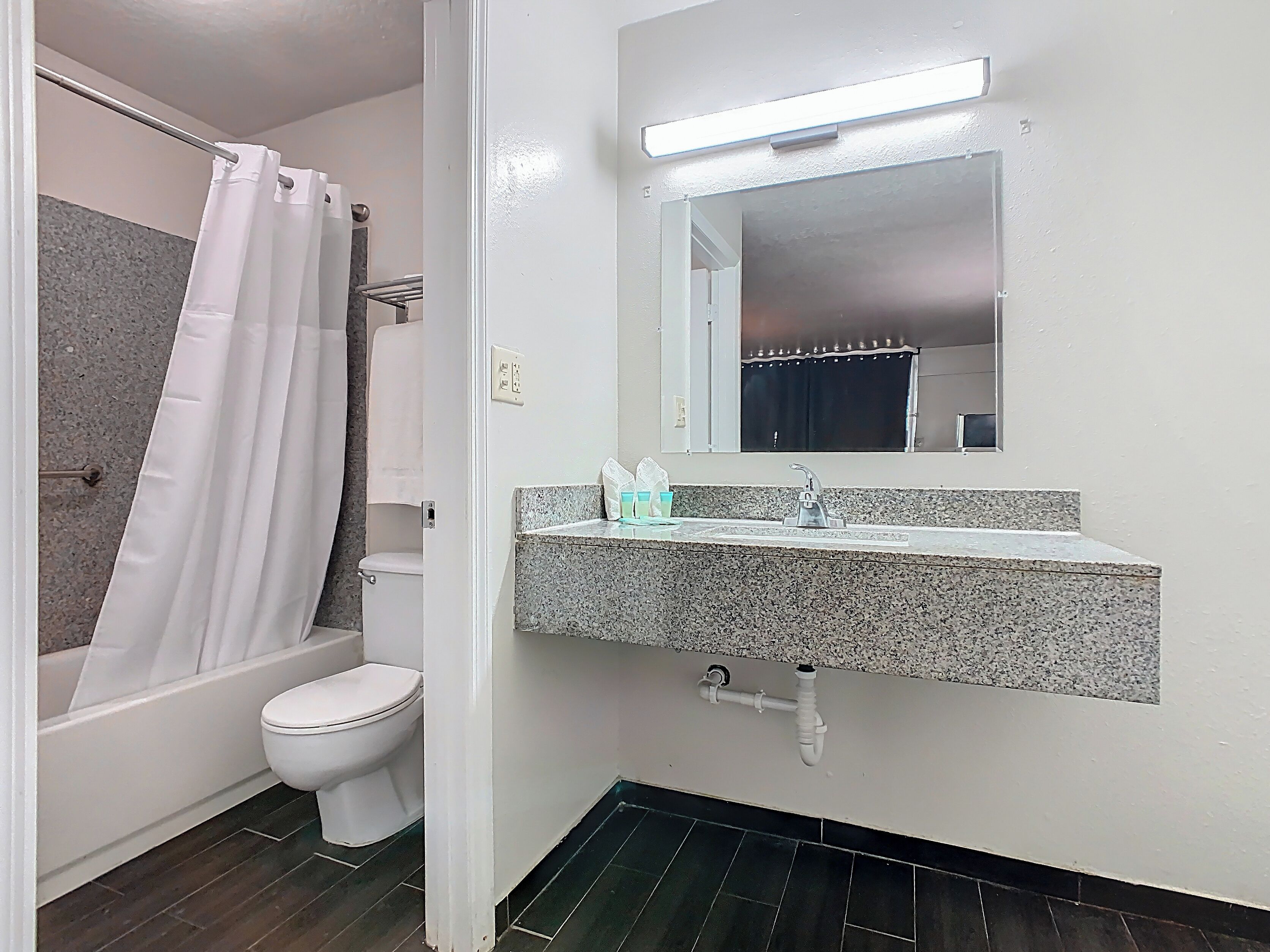 A bathroom with a shower, toilet, sink, and mirror.