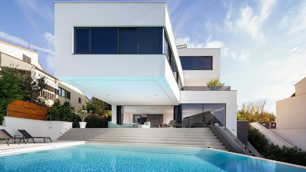 Una moderna casa a due piani con una piscina in primo piano.