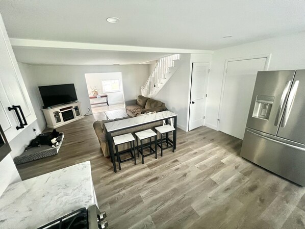 A modern kitchen with a central island, a built-in oven, and a stainless steel refrigerator.