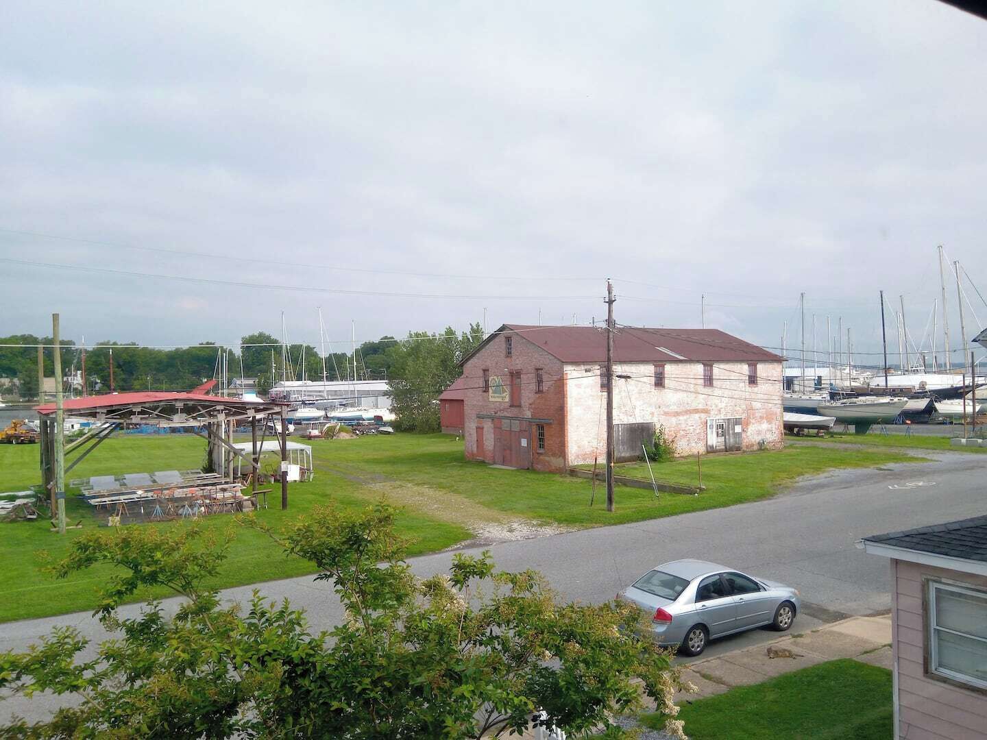 Un port de plaisance avec des bateaux, un petit bâtiment en briques et une voiture garée dans la rue.