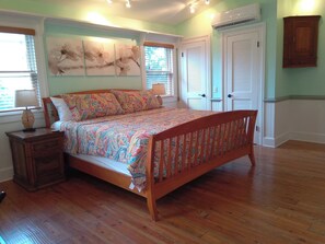A bedroom with a wooden bed, a nightstand, a lamp, and a wall with abstract art.