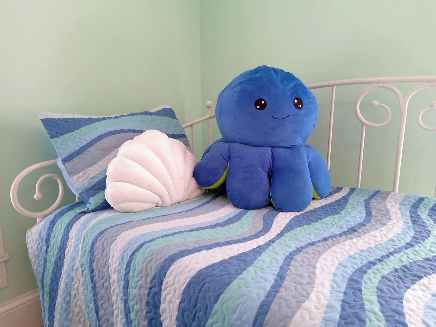 Ein Bett mit einem blauen Plüschtier und einem weißen Muschelkissen.