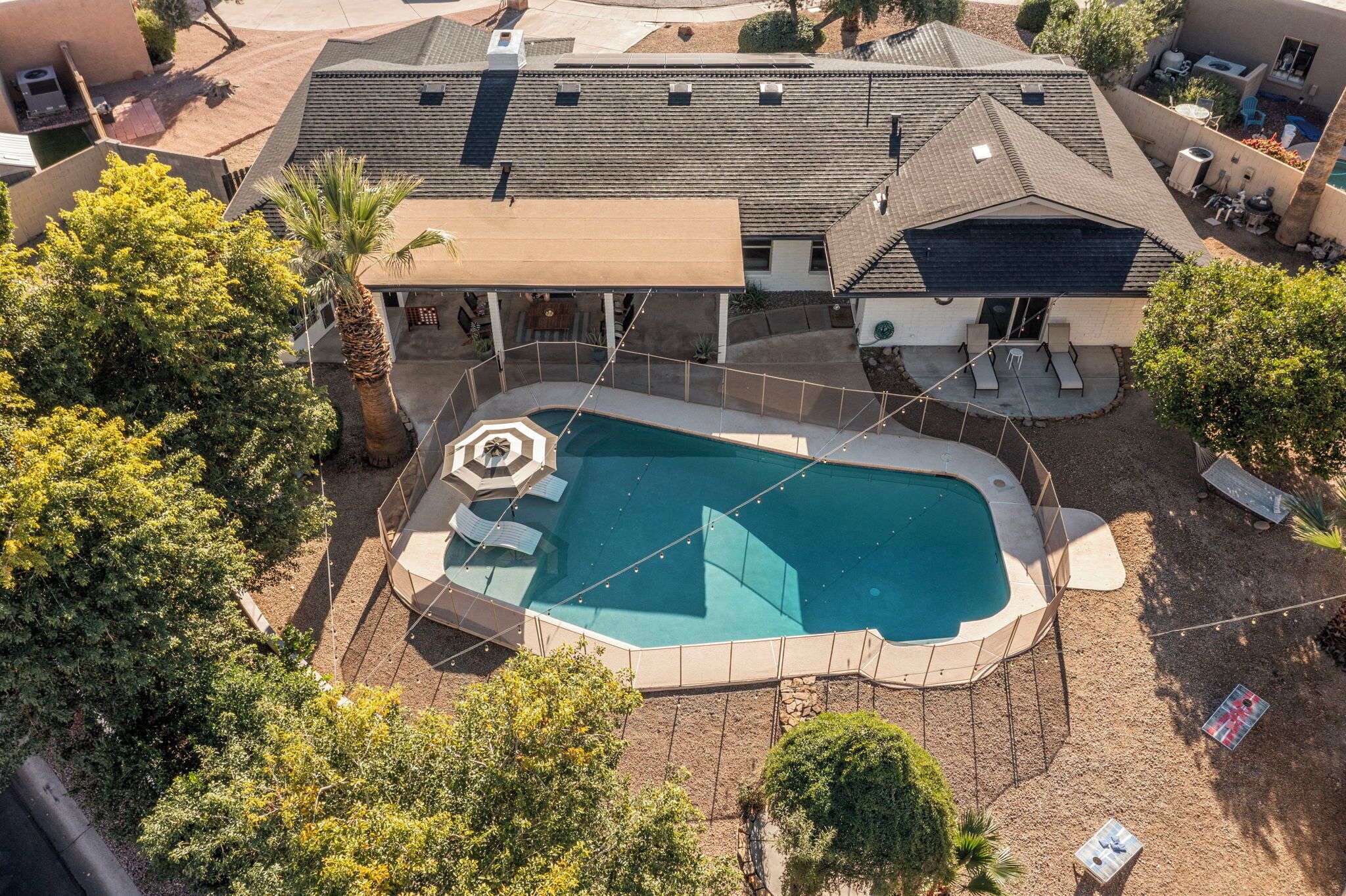 An aerial view of a residential property with a swimming pool, a covered patio, and a backyard deck.