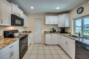 Features a stove, oven, and dishwasher, with a granite countertop and ample natural light.