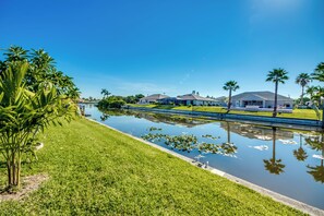 Stroll through a serene residential area surrounded by lush greenery and calm waters.