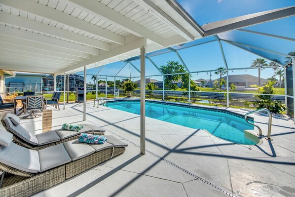 Relax by the pool surrounded by a spacious patio with a seating area and comfortable furniture.