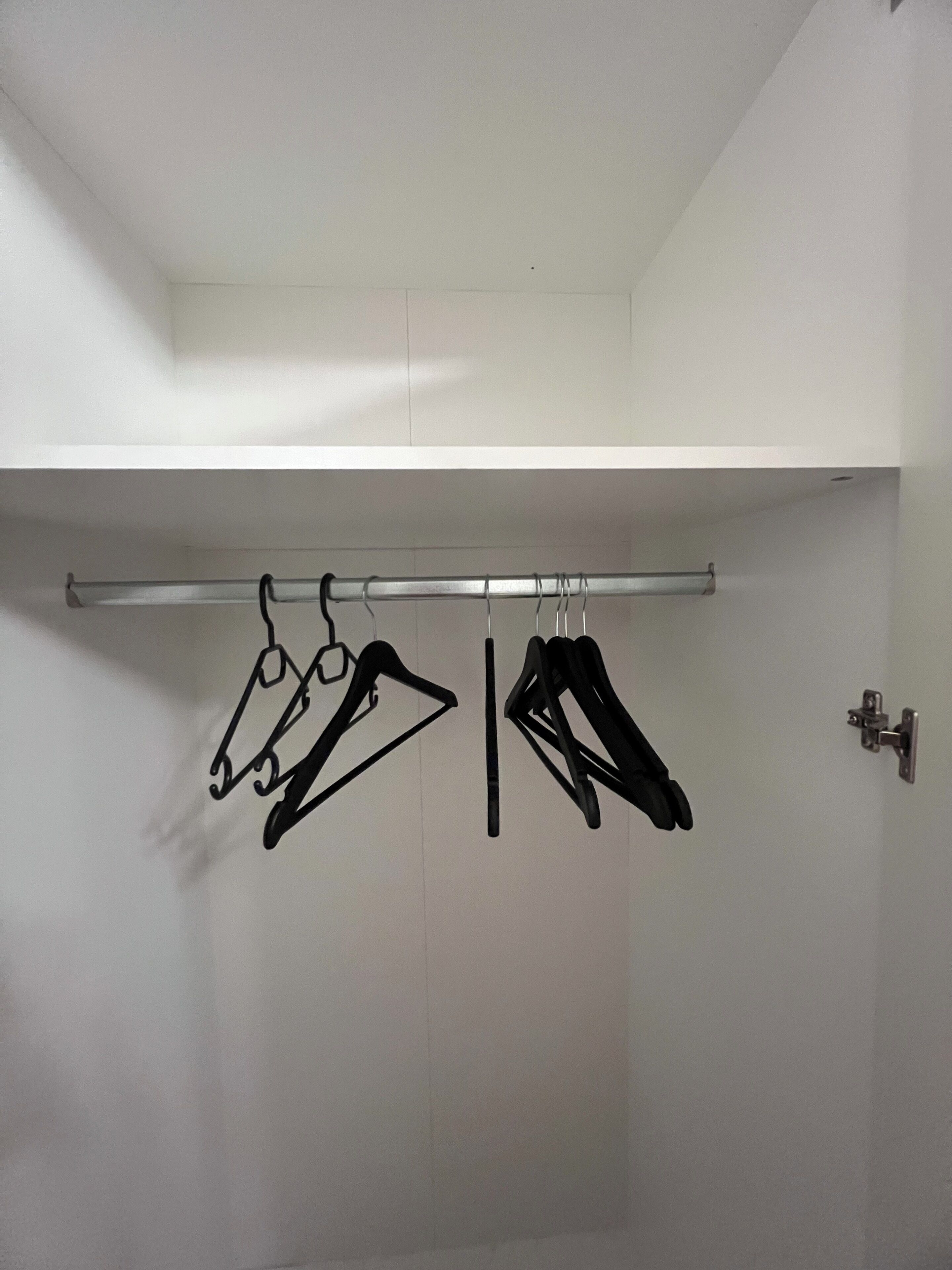 Un armario blanco con una barra metálica para colgar ropa.